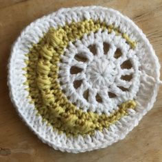 a white and yellow crochet dishcloth on a wooden table