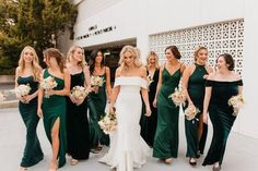 a group of bridesmaids standing in front of a building with their bouquets