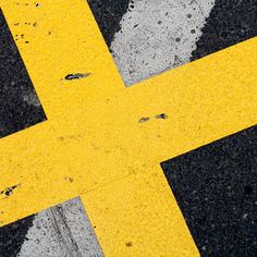 the yellow cross is painted on the black and white striped road marking something that looks like it has been vandalized