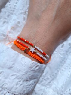 two orange and white beaded bracelets on a woman's wrist