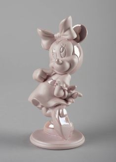 a figurine of a minnie mouse on a white base with a gray background