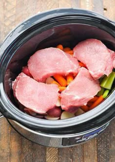 raw meat and vegetables in an electric pressure cooker on a wooden table with tongs