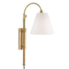 a wall lamp with a white shade on the side and a brass finish, it has a