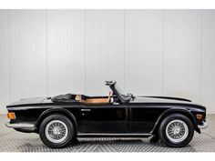 a black convertible car parked in front of a white wall