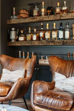 two leather chairs sitting in front of a shelf filled with liquor bottles