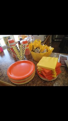 orange and yellow paper plates, napkins, and cups on a countertop in a kitchen