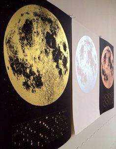 three black and gold moon paintings hanging on the wall