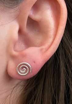 Beautiful textured 925 Sterling Silver Spiral stud earrings. These push back studs look amazing in all light with their delicately brushed finish. Metaphysical Benefits: The spiral is the rhythm of life. It characterizes the creative vital force of human and society, a symbol of unity of generations, and spiritual and moral growth of man. It means the life order, the symbol of continuity, development, motion, and journey into the unknown. Spiral Stud Earrings, Cute Studs Earrings, Cute Unique Earrings, Uneven Ear Piercings, Pretty Silver Earrings, Gold Spiral Jewelry, Cool Stud Earrings, Ear Piercings Grunge, Spiral Symbol Meaning