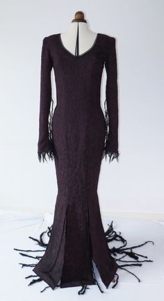 a mannequin wearing a purple dress with long sleeves and fringes on it