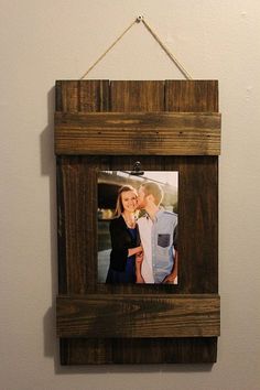 a wooden frame hanging on the wall with a couple holding each other and kissing in it