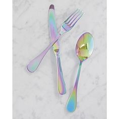 two spoons and one fork are sitting on a marble counter top, with iridescent colors