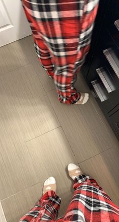 the person is wearing plaid pajamas and standing in front of an oven with their feet up