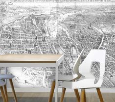 two white chairs sitting at a table in front of a wall with a map on it