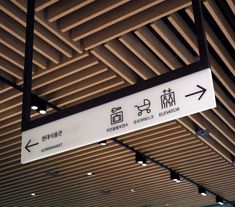 a white and black sign hanging from the ceiling in a room with wood slats