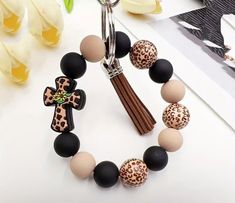 a bracelet with an animal print cross and tasseled beads is displayed on a table