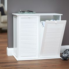 a white cabinet with shutter doors and shoes on the floor