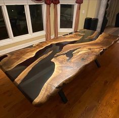 a large wooden table sitting on top of a hard wood floor next to a window