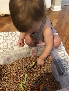 a young child playing with toys in a plastic container