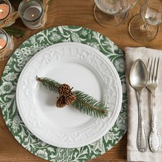 a white plate topped with a pine cone on top of a wooden table next to silverware