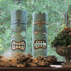 two totems sitting on a window sill next to a potted plant