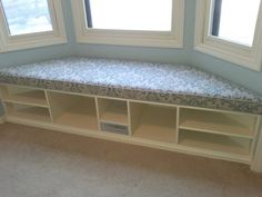 a room with two windows and a bench in the corner next to some bookshelves