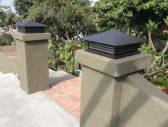 two black chimneys on top of a gray fence