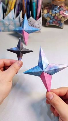 two hands are holding origami stars on a table