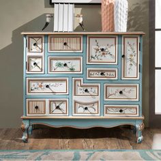 a blue and white dresser with flowers painted on the front, drawers decorated with books and vases