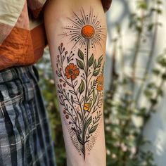 a woman's arm with flowers and sunbursts on the back of it