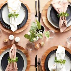 the table is set with black and white plates, silverware, napkins, and greenery