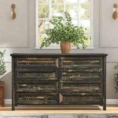 a large wooden dresser sitting in front of a window with potted plants on top