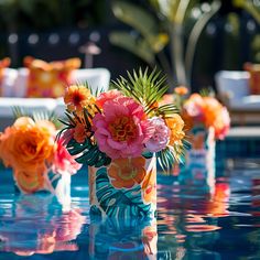 colorful flowers in vases sitting on the edge of a pool at a wedding reception