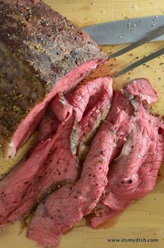 sliced meat sitting on top of a cutting board next to a knife