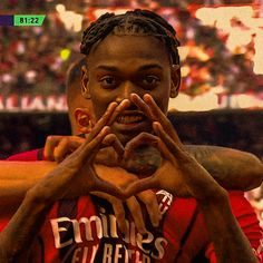 a man making a heart with his hands while standing in front of an audience at a sporting event