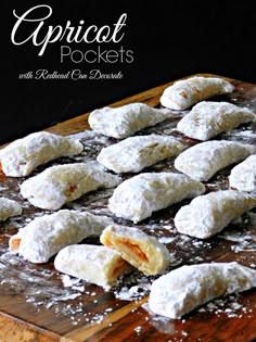 several pastries on a wooden cutting board with powdered sugar scattered around them,