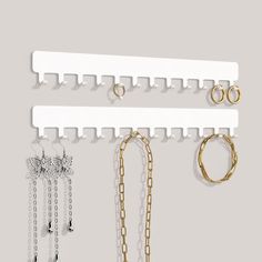 three pairs of jewelry hang on a white wall with gold chains and earring hooks