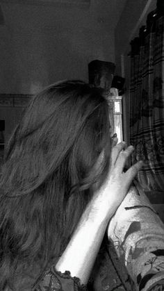 black and white photograph of a woman looking in the mirror with her hair blowing back