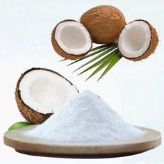 coconuts and sugar on a wooden spoon with palm leaves in the air above them