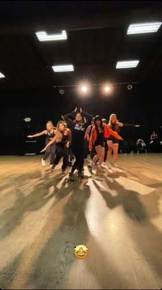 a group of people standing on top of a wooden floor next to each other in an empty room