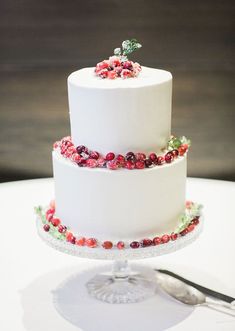 a three tiered white cake with cranberries on top