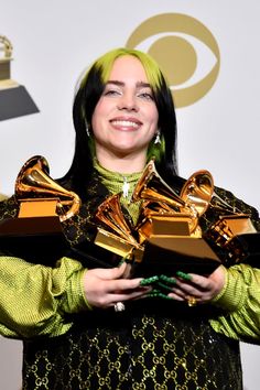 a woman with green hair holding two awards