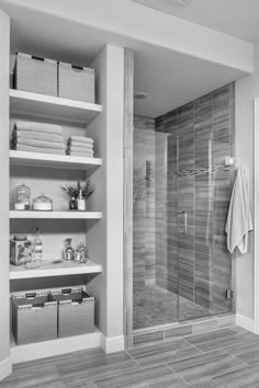 a walk in shower sitting next to a white shelf filled with towels and other items