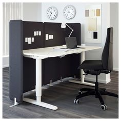 an office cubicle with a desk, chair and clock on the wall behind it