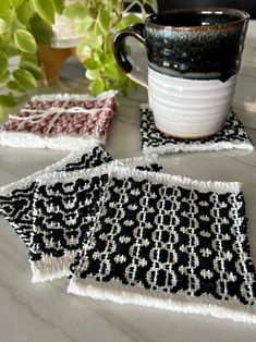 three black and white coasters sitting on top of a table next to a coffee cup