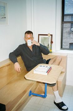 a man sitting on a bench drinking from a cup