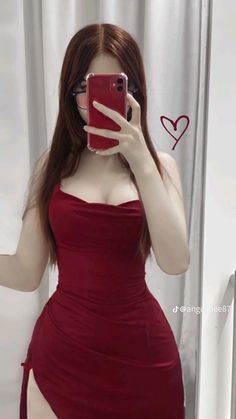 a woman taking a selfie in front of a mirror wearing a red dress and holding a cell phone up to her face