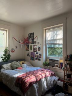 a bed sitting in a bedroom next to two windows with pictures hanging on the wall