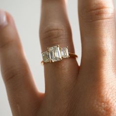 a woman's hand with a three stone diamond ring on top of her finger