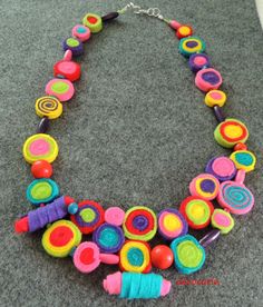 a multicolored necklace is displayed on the floor in front of a gray carpet