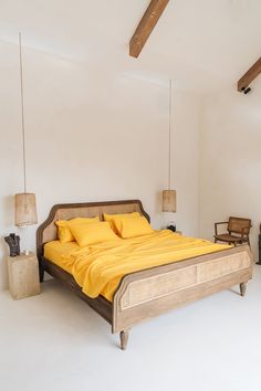 a bed with yellow sheets and pillows in a white room